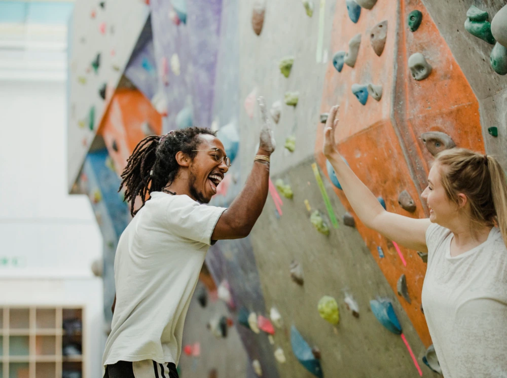 Climbing instructor is giving a high-five to a young woman he has been teaching.